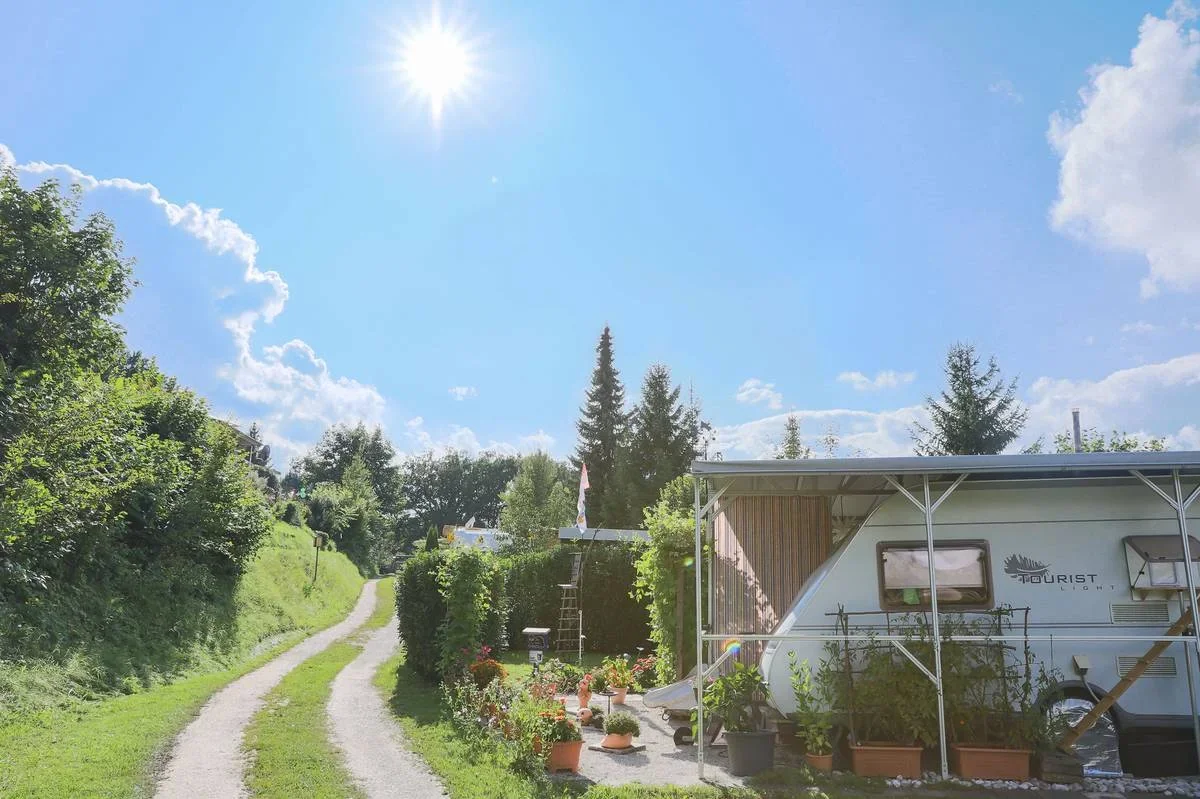 Weg entlang begrünten Dauerstellplätzen unter blauem Himmel.