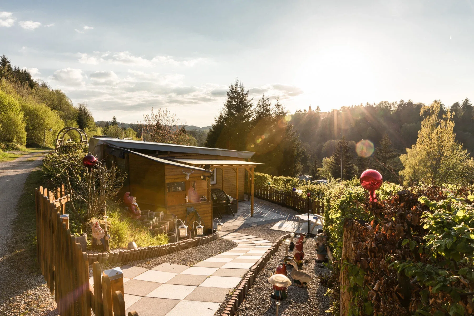 Terrasse und bepflanzter Dauerstellplatz im Abendlicht.