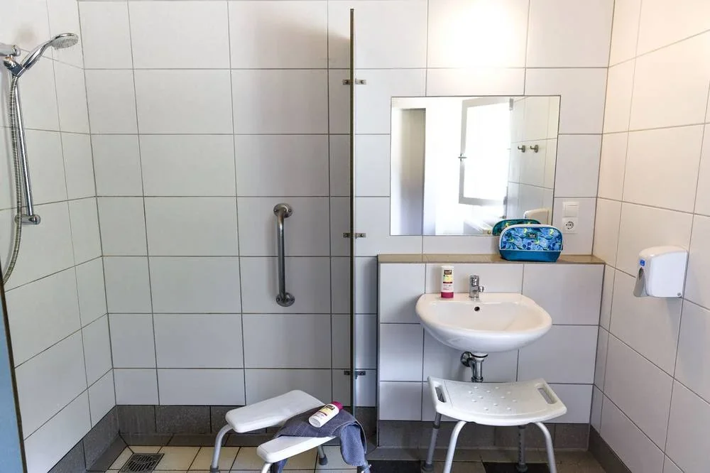 Dusche, Duschsitz und Waschbecken im separaten Sanitärraum.