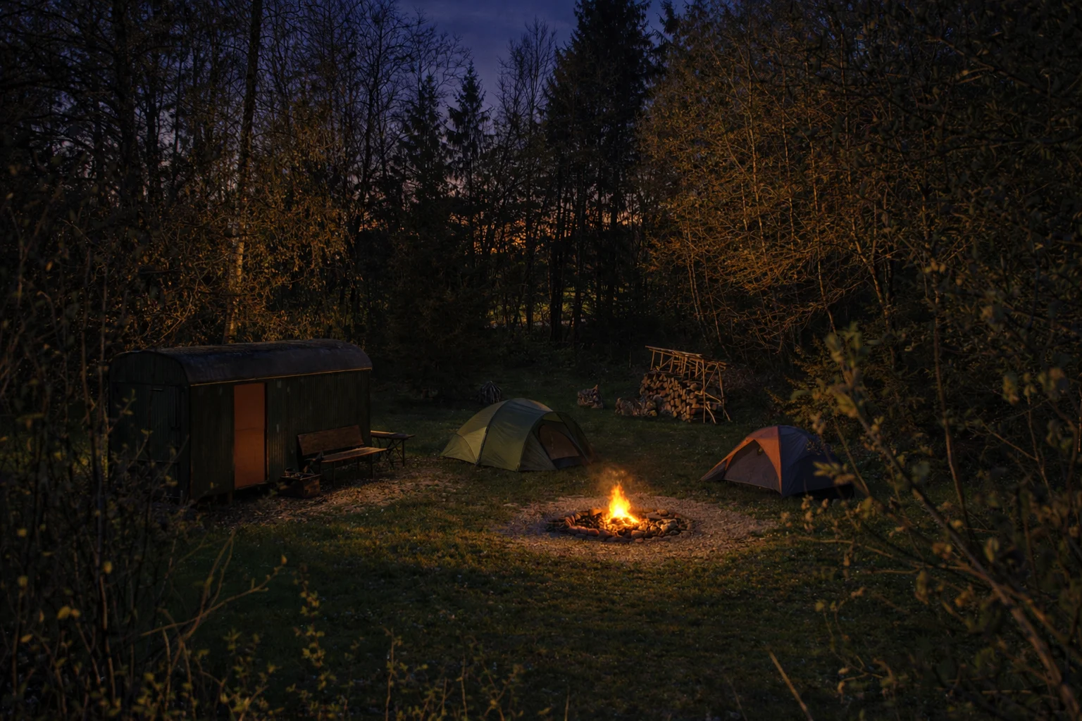 Zelte und Lagerfeuer am Waldrand in der Abenddämmerung. (KI-bearbeitet)
