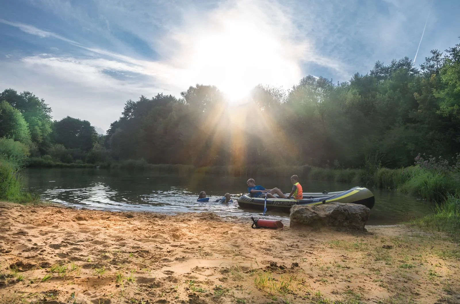Abendsonne über dem Weiher mit einem Schlauchboot am Ufer.